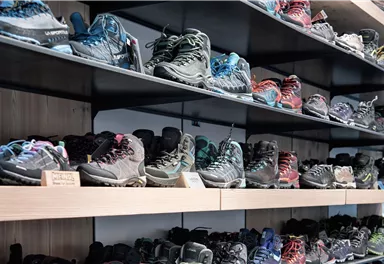 Eine Wand mit Regalen voller Wanderschuhe in verschiedenen Farben und Designs. Die Schuhe sind ordentlich angeordnet und ideal für Outdoor-Aktivitäten.