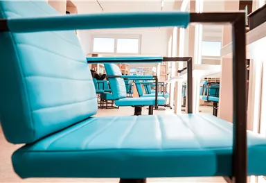 Ein moderner Raum mit hellblauen Stühlen. Die Stühle sind in einer Reihe angeordnet und strahlen ein einladendes Ambiente aus.