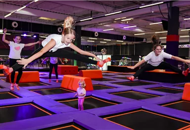 A trampoline park with several jumping girls. The atmosphere is lively and energetic.