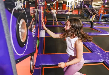 A girl jumps on trampolines and plays with interactive walls. It is a lively, fun environment for active leisure activities.
