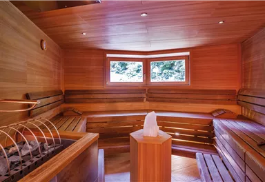 A cozy sauna with wooden paneling and windows that offer a view outside. The room is inviting and ideal for relaxing.