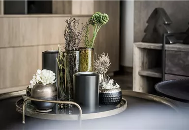 Ein stilvolles Arrangement mit Vasen und Kerzen auf einem Tablett. Die dekorativen Elemente bestehen aus Trockenblumen und verschiedenen Texturen.
