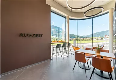 A modern room with large windows and a view of the mountains. There are stylish furnishings and the inscription "TIME OUT" on the wall.