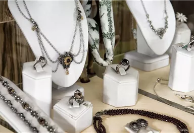 Jewelry display with various necklaces and rings. The pieces of jewelry are presented on white stands.
