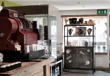 An elegant shop with a red cash register and a shelf full of jewelry. The room feels modern and inviting.