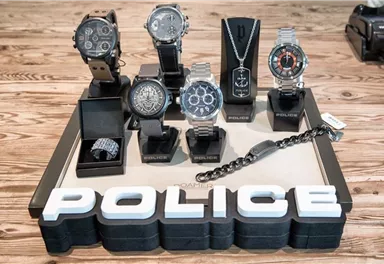 A collection of various police watches and jewelry on a display table. In the foreground is the word "POLICE" in large print.