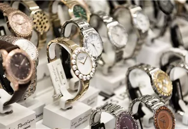 A range of wristwatches in various designs and materials. The watches are displayed on white stands and feature elegant dials.