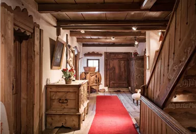 A cozy hallway with wooden furniture and a red carpet. The walls are made of wood, and there is a warm, inviting atmosphere.
