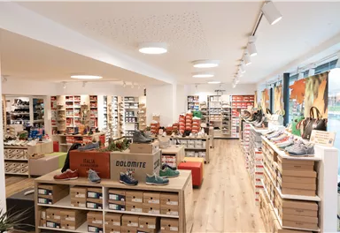 A modernly designed shoe store with bright shelves and a variety of shoes. The lighting creates an inviting atmosphere.