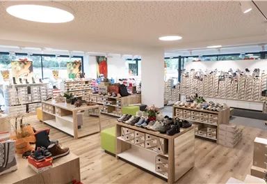 A modern shoe store with bright shelves and various shoe models. The atmosphere is inviting and well-lit.