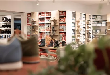 A shoe store with shelves full of shoes. In the foreground, several pairs of shoes are visible.