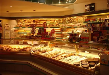 A bakery with a variety of freshly baked bread and pastries. The shelves are well stocked and the goods are attractively displayed.