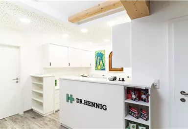 Eine moderne Praxis mit einem Empfangstresen von Dr. Hennig. Die Wände sind hell und die Einrichtung ist schlicht und funktional.
