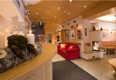An inviting foyer with a red sofa and a cozy fireplace. The wooden elements and subtle lighting create a warm atmosphere.