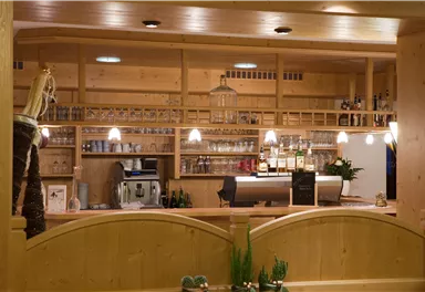 A cozy bar with wooden shelves and various alcoholic beverages. The lighting creates a pleasant atmosphere.