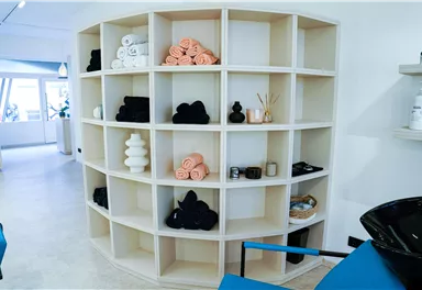 Ein moderner Regal mit verschiedenen Handtüchern und dekorativen Objekten. Der Raum wirkt hell und einladend.