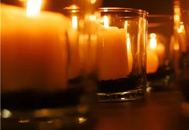 Kerzen in Glasbehältern leuchten sanft im Dunkeln. Ihre warmen Flammen schaffen eine gemütliche Atmosphäre.