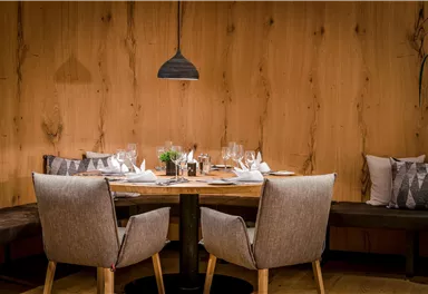 Ein stilvolles Restaurant mit einem Holztisch und eleganten Stühlen. Die Tischdekoration ist einfach und ansprechend, um eine einladende Atmosphäre zu schaffen.