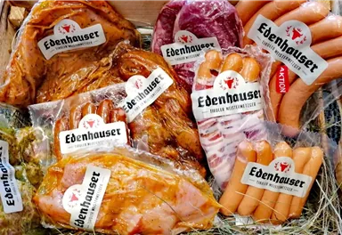 A selection of various meat products in packaging featuring the "Edenhauser" logo. Included are sausages, ribs, and other meat specialties.
