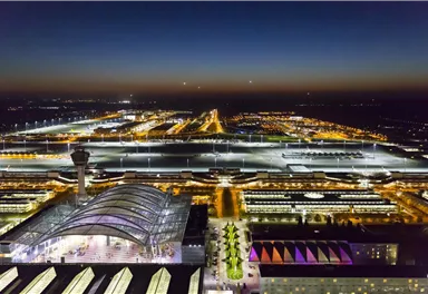 An airport at night with many lights and a clear structure. The view shows the terminal and the runways.