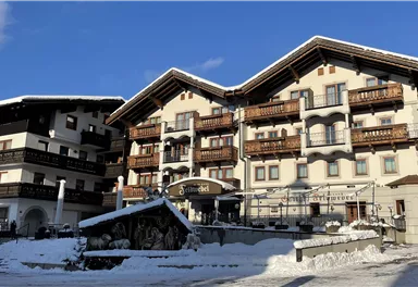 A cozy hotel in the mountains, surrounded by snow. The clear sky and alpine architecture create an inviting atmosphere.