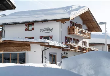 Ein gemütliches Chalet im Schnee mit Balkonen und traditionellen Fenstern. Die Umgebung ist von einer tiefen Schneeschicht bedeckt.