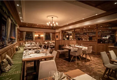 Ein gemütliches Restaurant mit Holzmöbeln und warmem Licht. Die Tische sind gedeckt und laden zum Essen ein.