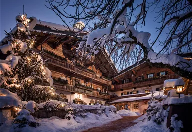 Ein wunderschönes Chalet, umgeben von schneebedeckten Bäumen und einem festlich geschmückten Weihnachtsbaum. Die Szene strahlt eine gemütliche Winteratmosphäre aus.