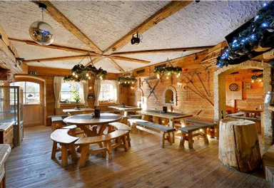 Ein gemütliches Restaurant mit Holztischen und Bänken. Die Räume sind rustikal eingerichtet und gut beleuchtet.
