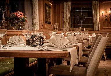 Ein elegantes Restaurant mit schön gedecktem Tisch. Die Dekoration umfasst fein gefaltete Servietten und Gläser in einer gemütlichen Holzumgebung.