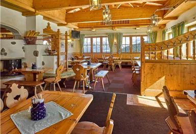 A cozy restaurant with wooden decor and several tables. Large windows provide plenty of natural light and an inviting atmosphere.