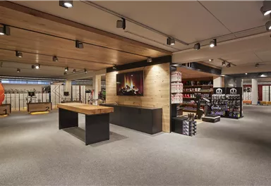Ein modernes Geschäft mit Holzregalen und einer zentralen Theke. Die Beleuchtung ist warm und schafft eine einladende Atmosphäre.