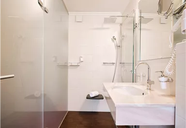 Ein modernes Badezimmer mit einer Dusche und einem Waschbecken. Die Wände sind hell und die Böden aus Holz.
