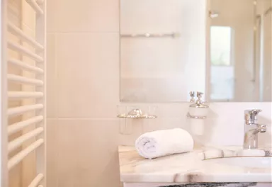 Ein modernes Badezimmer mit einer Marmortheke und einem Handtuch. Im Hintergrund ist ein großer Spiegel und eine elegante Armatur sichtbar.