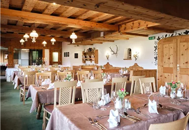 Ein gemütliches Restaurant mit Holzdekor und Tischen, die für Gäste gedeckt sind. Die Atmosphäre ist einladend und freundlich.