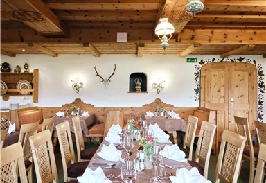 Ein gemütliches Restaurant mit Holzmöbeln und einer einladenden Atmosphäre. Der Tisch ist festlich gedeckt und die Wände sind mit antiken Elementen dekoriert.