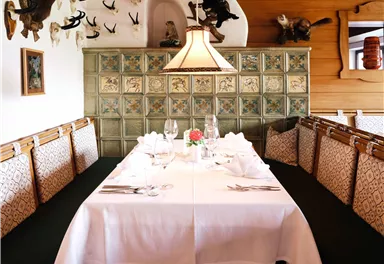 Ein gemütlicher Essbereich mit einem festlich gedeckten Tisch und dekorativen Wänden. Die Umgebung ist rustikal mit einer warmen Atmosphäre.