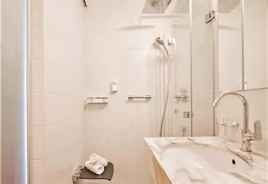 Ein modernes Badezimmer mit einer begehbaren Dusche und einem eleganten Waschbecken. Die Wände sind hell gefliest und sorgen für eine frische Atmosphäre.