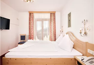 Ein helles Schlafzimmer mit zwei Einzelbetten und einer modernen Einrichtung. Der Raum ist mit einem Fernseher, einem Nachttisch und einem Stuhl ausgestattet.