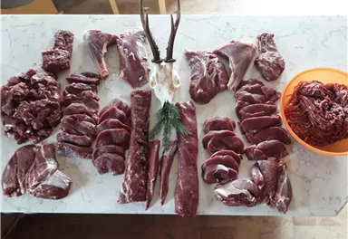 The image features various pieces of meat arranged on a table. In the center, there is a rack and a bowl with more meat.