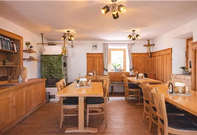 A cozy room with wooden tables and chairs. The walls are made of wood, and the light is warm and inviting.