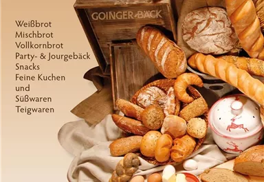 A selection of fresh breads and baked goods in a rustic basket. This includes various types of bread, rolls, and sweet treats.