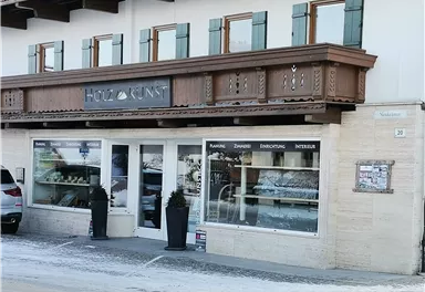 A cozy shop with an inviting display window. Above it is a wooden balcony with classic windows.