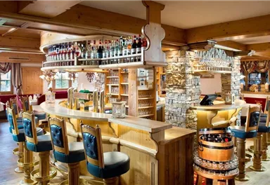 An elegant bar with wooden interiors and a variety of drinks. The space is cozily furnished and invites you to linger.