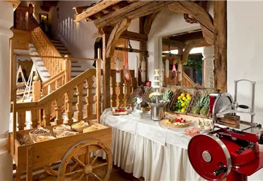 An inviting restaurant with a rustic atmosphere and a buffet of fresh food. In the background, there is a wooden staircase and decorative elements.