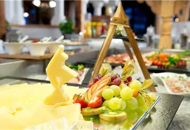 A rich buffet with fresh fruit and decorative cheese. The presentation is appealing and inviting.
