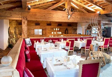 A cozy restaurant with wooden interiors and elegant tables. Red seats and rustic elements create an inviting atmosphere.