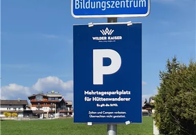 Ein Parkplatzschild für ein Bildungszentrum. Darunter befindet sich ein zusätzliches Schild für Halteplätze.