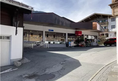 Ein modernes Geschäft in einer malerischen Umgebung. Die Straße verläuft sanft und es sind Einkaufwagen vor dem Eingang zu sehen.