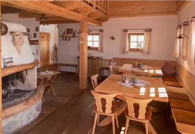 A cozy room with wooden furniture and a fireplace. There are tables and chairs, as well as windows with a view outside.